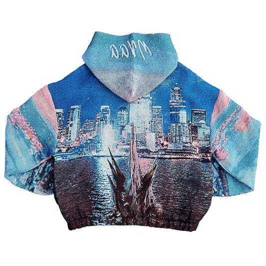 A boxy fit pullover hoodie featuring a detailed skyline and waterfront of Seattle and a monster lurking in the darkness