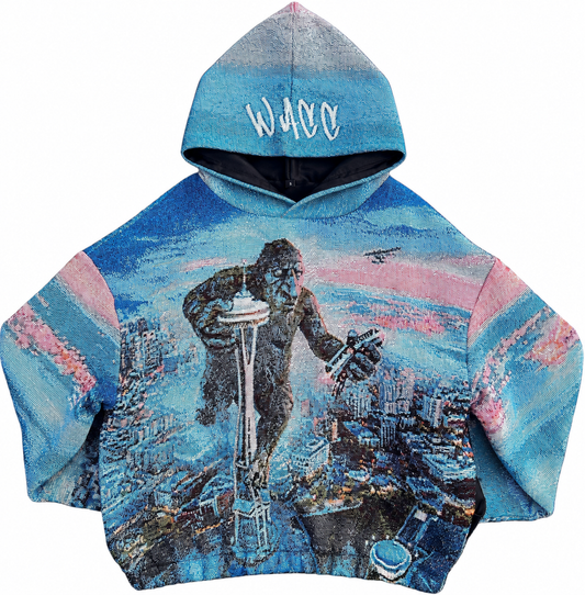 A hooded sweatshirt featuring a full-color graphic of a Fremont Troll standing on Seattle Space Needle, crushing monorail with seaplane hovering above him