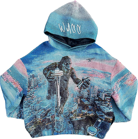A hooded sweatshirt featuring a full-color graphic of a Fremont Troll standing on Seattle Space Needle, crushing monorail with seaplane hovering above him