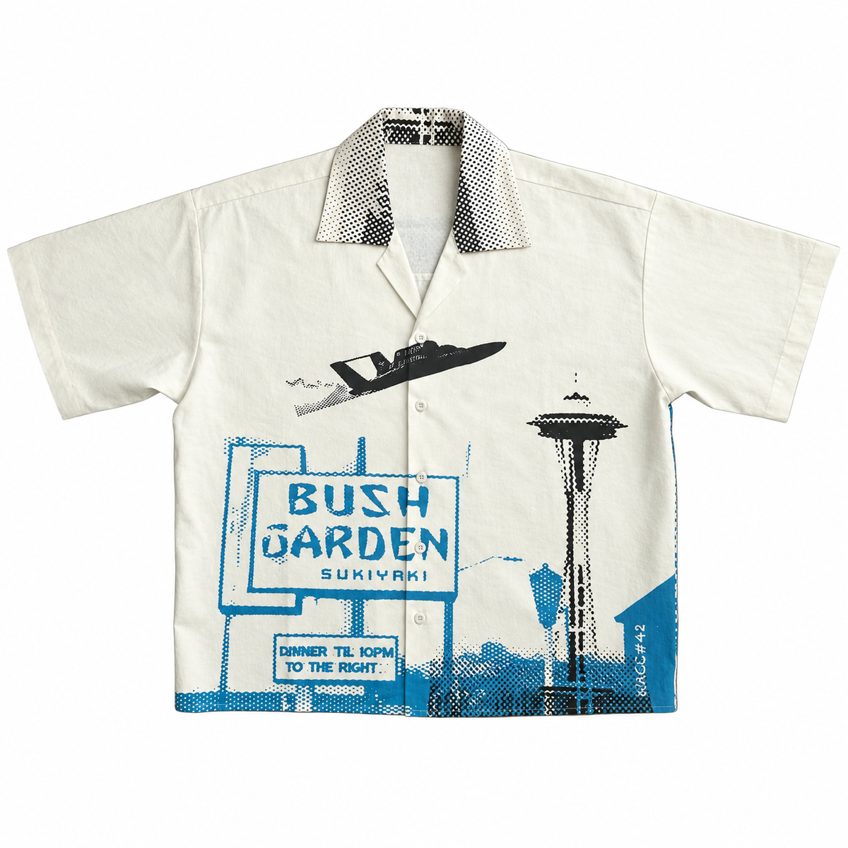 A short-sleeve camp collar button-up shirt in off-white, featuring a blue and black graphic print of the Bush Garden Sukiyaki sign, a hydroplane, and the Seattle Space Needle.