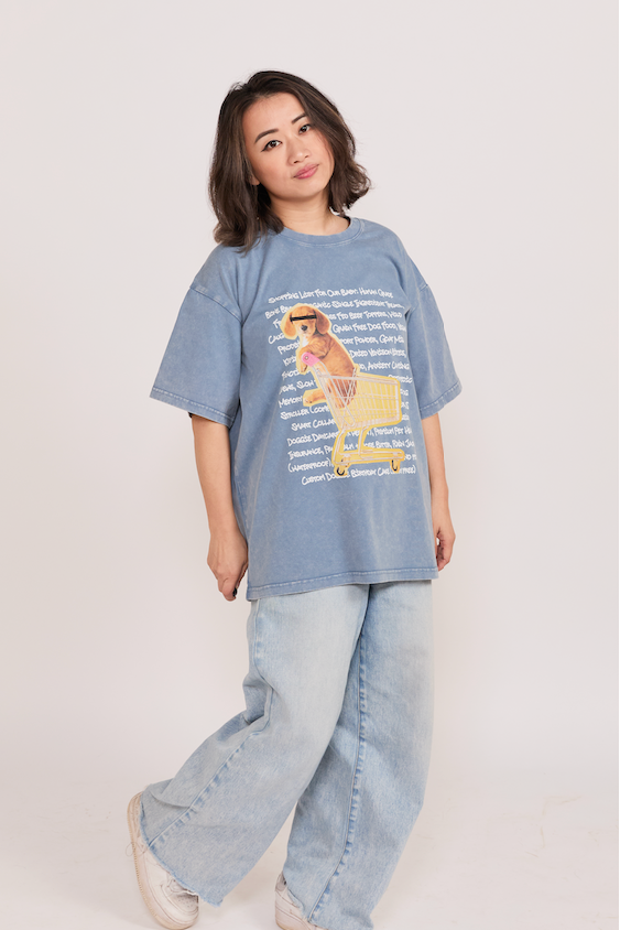 Person wearing a blue oversized t-shirt with a graphic design on a plain background
