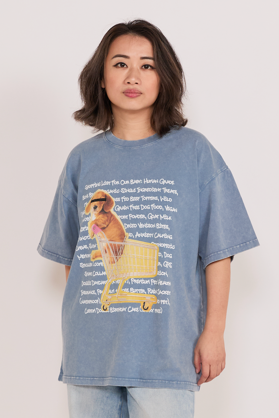 Person wearing a blue oversized t-shirt with a graphic design on a plain background