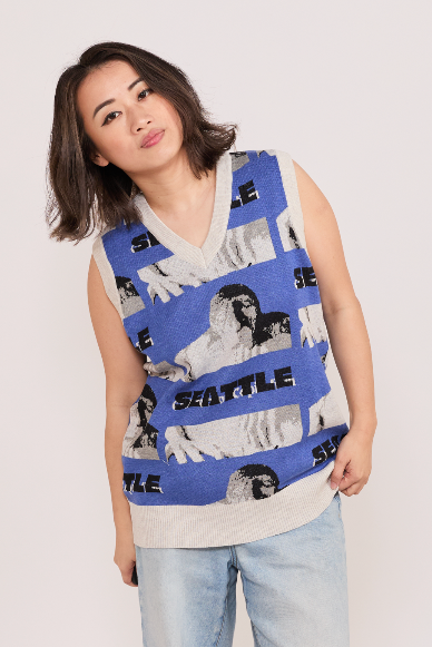 Woman wearing a blue sleeveless knitted vest with 'Seattle' text and Troll images